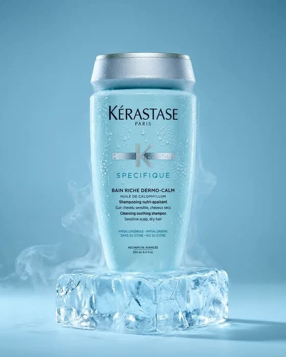 The same bottle standing on a block of ice in cold blue light, mist around the base