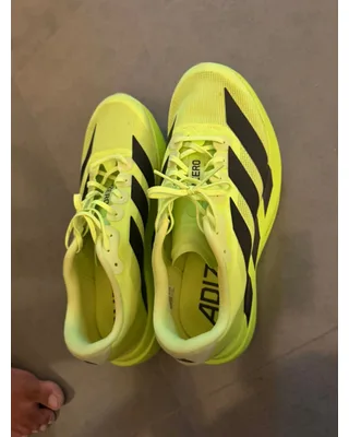 A phone snapshot of neon yellow running shoes on a carpet