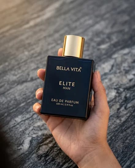 The same bottle held in one hand above dark slate